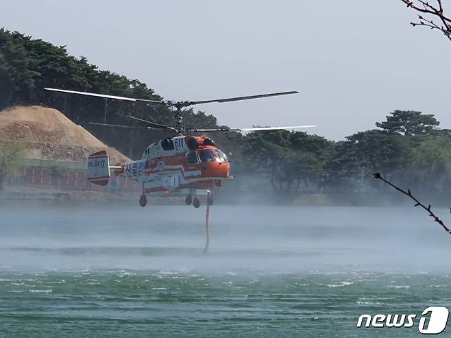 제천시 봉양읍 봉화산에서 발생한 산불을 진화하기  위해 산불진화용 헬기가 의림지에서 물을 퍼 올리고 있다