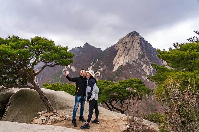 북한산 영봉에서 인수봉을 배경으로 기념 사진을 남기는 청춘의 모습. 지난해 국내 입국 규제가 대폭 완화된 이후로 북한산을 찾는 외국인도 크게 늘었다.