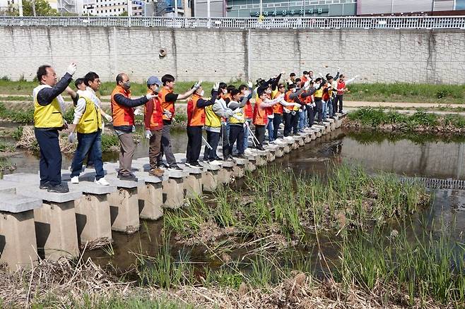 SK실트론과 구미시설공단 임직원들이 경북 구미시 이계천 하천정화를 위해 EM 흙공을 던지고 있다. SK실트론 제공