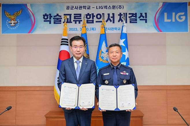 LIG넥스원 이건혁 PGM사업부문장(왼쪽)과 이상학 공군사관학교장이 지난 30일 충북 청주시 공군사관학교에서 열린 '공동연구를 통한 공군 무기체계 발전방향 제시 및 미래 첨단무기체계 운용개념 수립' 업무협약식에서 학술교류 합의서를 들고 기념 촬영을 하고 있다. LIG넥스원 제공