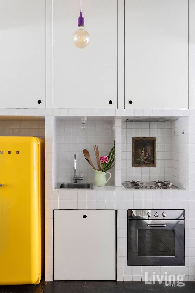 흰색 주방 가구와 노란색 스메그 냉장고가 포인트인 주방. 펜던트 조명은 무토 muuto.com의 E27.