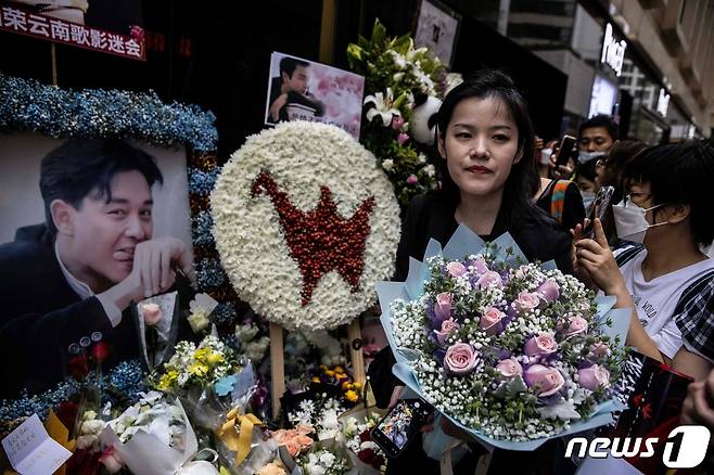 홍콩의 가수 겸 배우였던 장국영 사망 20주기를 맞은 1일(현지시간) 홍콩에서 한 시민이 장국영의 사진 앞에 분홍색 장미 꽃다발을 바치고 있다. 2023.04.01. ⓒ AFP=뉴스1 ⓒ News1 김성식 기자
