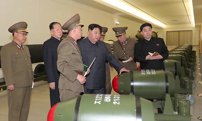 김정은 북한 국무위원장이 지난달 27일 핵무기 병기화사업을 지도하면서 전술핵탄두 앞에서 관계자로부터 설명을 듣고 있다. 조선중앙TV·뉴시스
