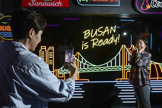 Models take a picture with a Galaxy S23 Ultra smartphone inside a photo booth set up by Samsung Electronics at Gwanghwamun Square in central Seoul. Visitors can use the Galaxy S23 Ultra model with an improved Nightography feature to take a picture inside a dark room. [SAMSUNG ELECTRONICS]