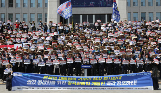 3일 오후 서울 여의도 국회 본청 앞에서 열린 더불어민주당 쌀값 정상화법 공포 촉구 결의대회에서 참석자들이 손피켓을 들고 구호를 외치고 있다. 2023.4.3. 뉴스1