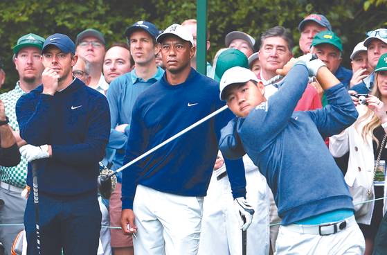 Tom Kim hits his tee shot on the 14th hold during a practice round ahead of The Masters as Rory McIlroy and Tiger Woods look on at the Augusta National Golf Club in Augusta, Georgia on Monday.  [REUTERS/YONHAP]