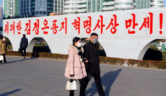 북한 평양 류경체육관 인근에 적힌 김정은 국무위원장 찬양 구호 앞에서 시민들이 이동하는 모습. AP·VOA 홈페이지 캡처