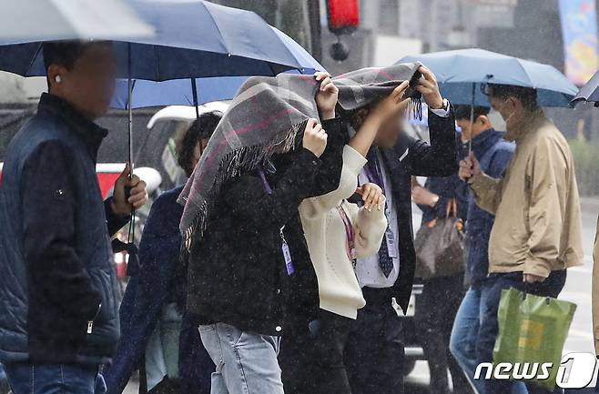 부슬비가 내린 6일 서울 시내 한 거리에서 우산을 챙기지 못한 시민들이 담요로 머리를 가리며 길을 지나가고 있다. 2023.4.6/뉴스1 ⓒ News1 김도우 기자