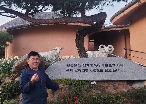 신탁열 대표가 골망태펜션·정원에 있는 자신의 인생좌표를 새긴 비석을 배경으로 포즈를 취하고 있다.