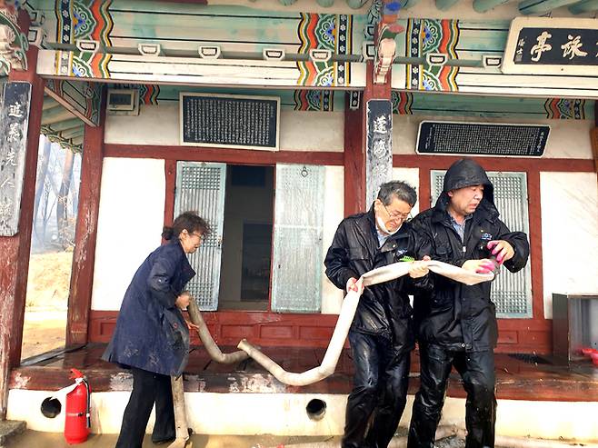 [강릉=뉴시스] 김경목 기자 = 11일 오전 강릉시청 공무원들이 강릉시 저동 '방해정(放海亭)'에서 주변 소화전에서 소방호스를 끌어와 정자에 물을 뿌리며 필사적으로 화마로부터 지켜내고 있다. (사진=강릉시청 제공) 2023.04.12. photo@newsis.com *재판매 및 DB 금지