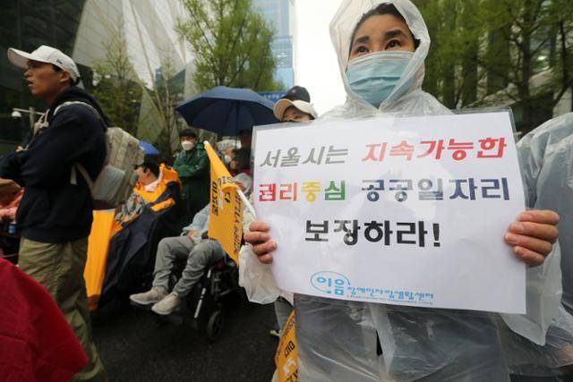 전국장애인차별철폐연대 소속 한 회원이 이달 6일 오후 서울 중구 서울시청 인근에서 열린 중증장애인 공공일자리 확대 요구 집회에서 피켓을 들고 서 있다. 뉴시스