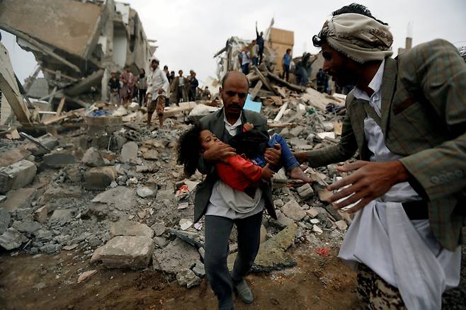 지난 2017년 예멘 수도 사나에 사우디 아라비아 군이 가한 공습으로 무너진 건물 잔해에서 한 소녀가 구출되고 있다. [로이터]