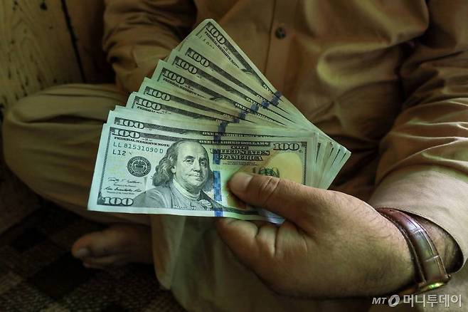 A trader displays U.S. dollar banknotes at a currency exchange booth in Peshawar, Pakistan September 15, 2021. REUTERS/Fayaz Aziz/File Photo