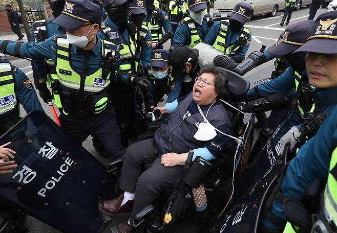 이형숙 전국장애인차별철폐연대 공동상임대표가 20일 서울 영등포구 63컨벤션센터 앞에서 열린 '장애인의날을 거부하는 자들의 장애인차별철폐의날 기념식'에서 차도 점거를 시도하자 경찰이 제지하고 있다. 뉴시스