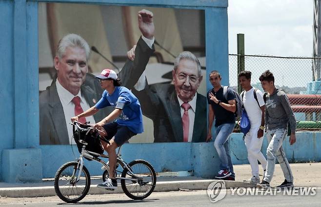 라울 카스트로(오른쪽)와 미겔 디아스카넬 대형 사진 지나는 쿠바 시민들 (아바나 EPA=연합뉴스) 19일(현지시간) 쿠바 아바나 한 거리에서 시민들이 라울 카스트로(오른쪽) 전 쿠바 공산당 제1서기와 미겔 디아스카넬 대통령 사진이 붙은 거리를 지나고 있다. 2023.4.20