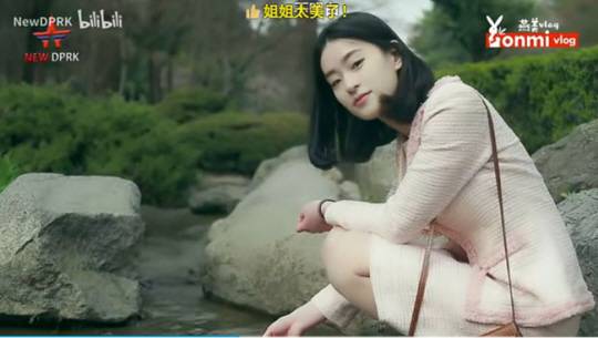 핑크색 투피스 차림의 북한 여성이 봄을 맞은 북한의 모습을 배경으로 포즈를 취하고 있다. “누나(언니) 너무 예쁘다”는 실시간 댓글이 보인다.  중국 빌리빌리 ‘연미 브이로그’ 캡처.