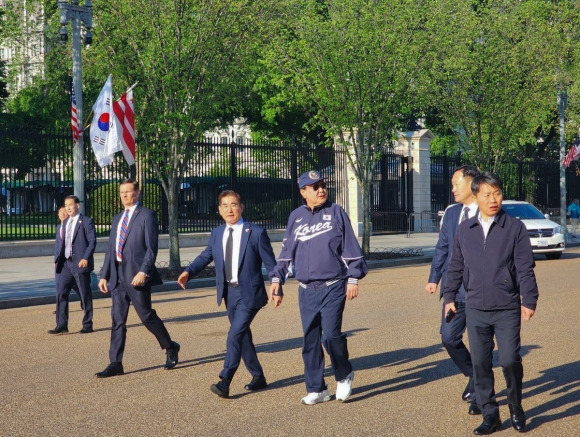 미국을 국빈 방문한 윤석열 대통령이 25일(현지시간) 워싱턴DC 백악관 인근에서 바이든 대통령이 지난해 방한 당시 선물한 모자와 선글라스, 대한민국 국가대표 야구팀 점퍼와 시구 때 신었던 국산 브랜드의 운동화를 신고 산책하고 있다.  2023.4.26 대통령실 제공