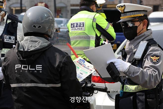 27일 서울 강남구의 한 교차로에서 경찰관들이 ‘우회전 일시멈춤’ 단속 중 적발된 운전자에게 안내문을 전달하고 있다. 조태형 기자