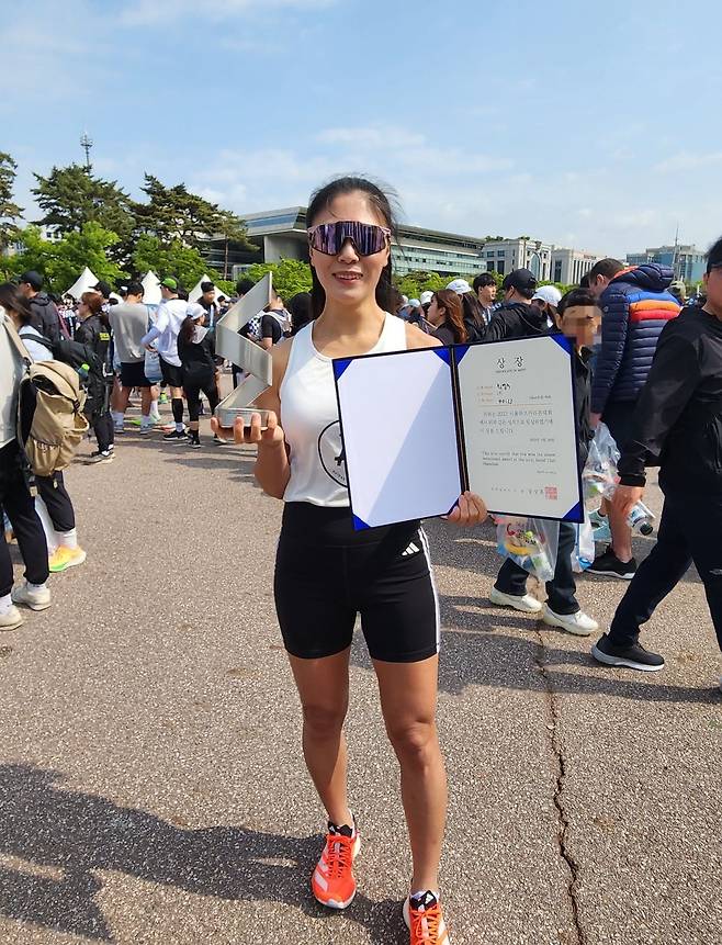 2023 서울하프마라톤 10km 부문 여자 1위 최영주씨가 30일 여의도공원에서 상장 및 트로피와 함께 기뻐하고 있다. 직장인인 그는 2주 전엔 보스턴 마라톤 풀코스를 뛰고 이번 대회에 참가하는 강철 체력을 과시했다. /박강현 기자