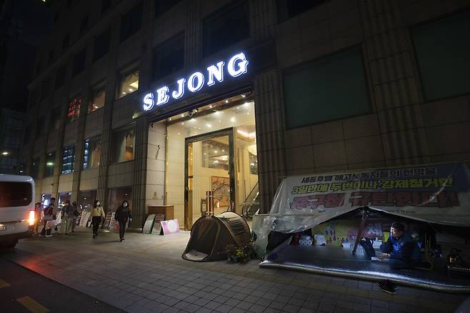 고진수 세종호텔 지부장이 농성장에 앉아 단체 관광객들이 버스에서 내리는 모습을 지켜보고 있다. ⓒ시사IN 이명익