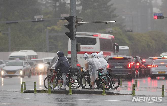 [제주=뉴시스] 우장호 기자 = 어린이날 황금연휴를 앞둔 4일 오전 제주국제공항 인근 횡단보도 앞에서 우비를 입은 자전거 여행족이 신호를 기다리고 있다. 기상청에 따르면 오는 6일 오전까지 제주를 포함한 전국 대부분 지역에 강한 바람을 동반한 많은 비가 내릴 것으로 전망된다. 2023.05.04. woo1223@newsis.com