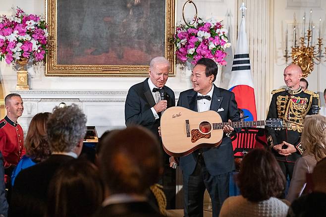 4월 26일(현지 시각) 미 백악관에서 열린 국빈 만찬에서 조 바이든 대통령이 윤석열 대통령에게 가수 돈 매클레인의 친필 사인이 새겨진 통기타를 깜짝 선물하고 있다. /UPI 연합뉴스