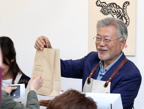 문재인 전 대통령이 지난달 26일 오후 경남 양산시 하북면 자신의 책방 '평산책방'에서 계산 업무를 하며 책을 손님에게 건네고 있다. 연합뉴스