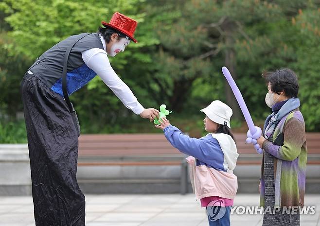 청와대 놀이터서 만난 피에로 (서울=연합뉴스) 김성민 기자 = 7일 오전 청와대 헬기장에 마련된 청와대 놀이터에서 열린 '청와대 웃음꽃이 피었습니다' 행사에서 한 어린이가 피에로 복장을 한 진행요원에게 풍선을 받고 있다. 이번 행사는 어린이날인 5일 진행될 예정이었으나 비로 인해 이날 진행됐다. 2023.5.7 ksm7976@yna.co.kr