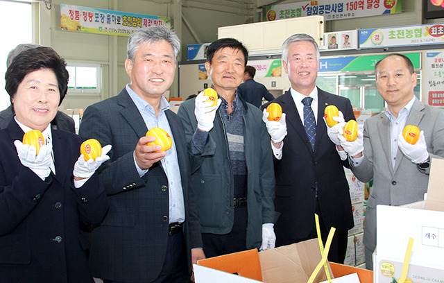 송준국 경북 성주 초전농협 조합장(오른쪽 두번째), 이주호 NH농협 성주군지부장(맨 오른쪽), 농협 임원 등이 4월27일 농산물 산지공판장 승격 기념행사 후 경매가 한창인 참외를 들어 보이며 활짝 웃고 있다.