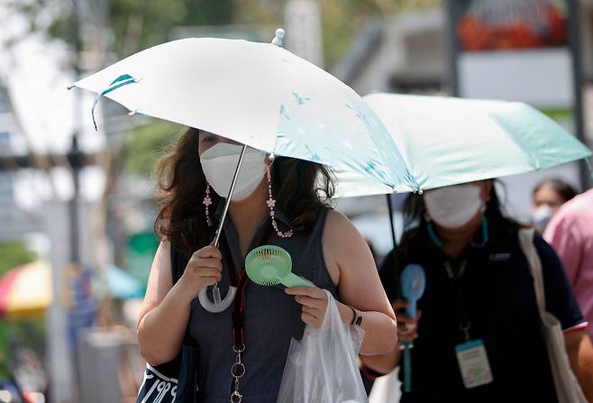 지난달 28일 태국 방콕에서 한 시민이 폭염에 우산을 사용하여 햇빛을 가리고 휴대용 선풍기로 더위를 식히고 있다./EPA 연합뉴스