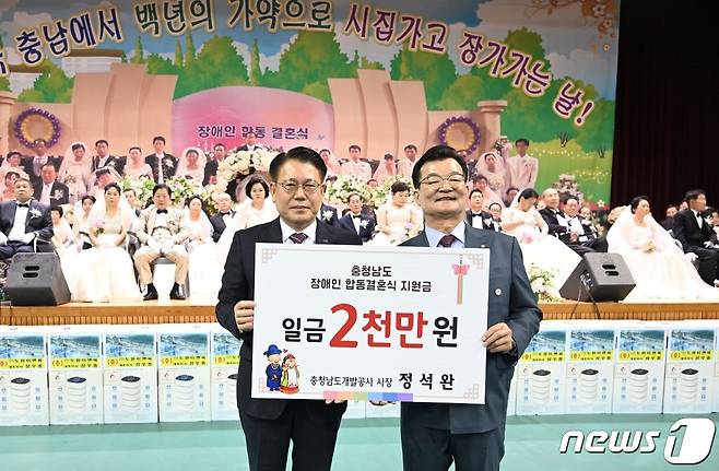 충남장애인합동결혼식이 열린 서산시민체육관에서 10일 충남개발공사 정석완 사장(왼쪽)이 장애인 부부 가정에 2000만 원을 기탁하고 있다.(충남개발공사 제공)/뉴스1