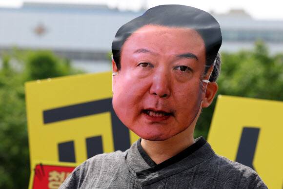 윤석열 대통령 취임 1주년인 10일 오전 서울 용산구 대통령 집무실 앞에서 열린 전국교직원노동조합원의 윤석열 정부 교육분야 규탄 기자회견에서 한 참가자가 대통령 가면을 쓰고 있다. 이들은 교사 인원 확충및 실질적 임금 인상, 교사 교육권 확보 등을 촉구했다. 연합뉴스