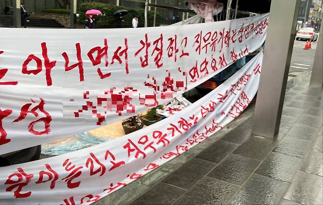 서울 강남구에 위치한 한 대기업 사옥 앞에 회사를 비판하는 빨간 글씨의 현수막이 걸려있다. [독자 제공]