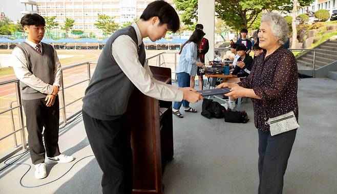 [광주=뉴시스] 변재훈 기자 = 광주 동신고등학교는 11일 졸업생 고(故) 정영훈씨의 이름을 딴 장학회가 학생 3명에게 장학금을 수여했다고 밝혔다. 장학금 재원을 기탁한 정씨의 어머니 김순희(70)씨가 이날 장학금을 전달하고 있다. 정영훈 장학회는 세상을 떠난 그의 교통사고 보상금을 재원으로 설립, 20년째 장학사업을 벌이고 있다. (사진=광주 동신고 제공) 2023.05.11. photo@newsis.com *재판매 및 DB 금지