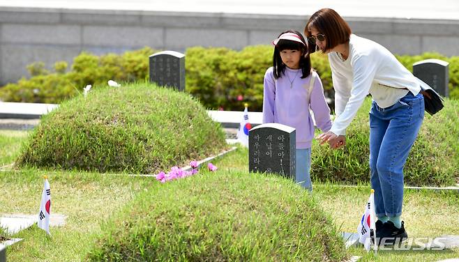 [광주=뉴시스] 이영주 기자 = 5·18민주화운동 제43주기를 닷새 앞둔 13일 오전 광주 북구 운정동 국립5·18민주묘지에서 한 어머니가 딸에게 5·18을 가르치고 있다. 2023.05.13. leeyj2578@newsis.com