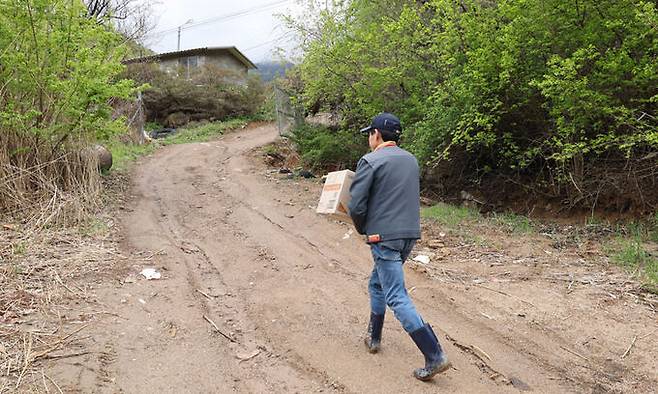 택배 박스를 든 김상준 집배원이 보트에서 내려 배달 가정으로 향하고 있다.