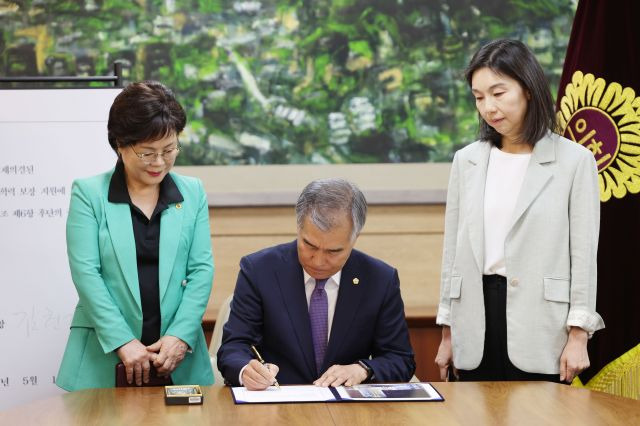 김현기 서울시의회 의장이 15일 오전 서울시의회에서 서울특별시교육청 기초학력 보장 지원에 관한 조례를 의장 직권으로 공포, 조례안에 서명하고 있다. 왼쪽부터 이경숙 서울시의회 서울교육 학력향상 특별위원장, 김 의장, 최호정 서울시의회 국민의힘 원내대표. 연합뉴스