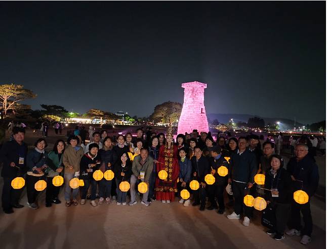 참가자들이 백등을 손에 들고 신라달빛기행 중 첨성대 앞에서 기념 촬영을 하고 있다.