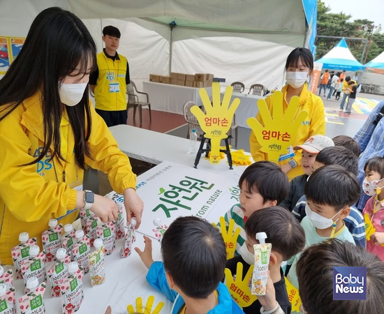 김미수 세이프키즈코리아 안전강사(왼쪽)가 13일 여의도공원에서 '엄마손캠페인' 부스에 참여한 어린이에게 자연원 유기농주스를 나눠주고 있다. ⓒ세이프키즈코리아