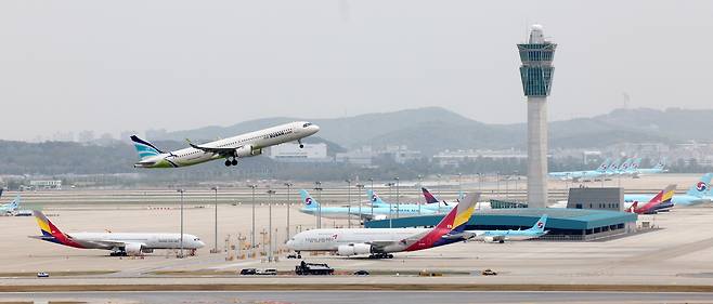 지난달 24일 인천국제공항 주기장에 세워진 대한항공, 아시아나항공 여객기 위로 에어부산 여객기가 이륙하고 있다./연합뉴스