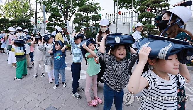 머리부터 안전하게 보호하고 (서울=연합뉴스) 홍해인 기자 = 16일 오후 정부서울청사에서 열린 414차 민방위의 날, 민방공 대피 훈련에 참여한 청사 푸르미어린이집 원아들이 머리를 가방으로 가린 채 청사 앞뜰 안전교육 장소로 이동하고 있다. 2023.5.16 hihong@yna.co.kr