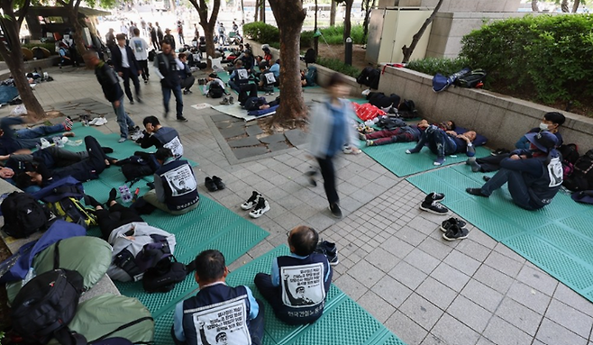 17일 오전 출근시간대 시민들이 서울 중구 청계광장에서 전날 밤 총파업 결의대회 후 노숙하고 있는 민주노총 건설노조원들을 지나치고 있다. ⓒ연합뉴스