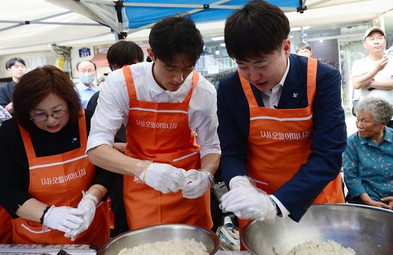 전두환 전 대통령의 손자 전우원씨가 17일 오후 광주 동구 금남로에 열린 전야제에 참석해 김형미 오월어머니집 관장(왼쪽)과 이준석 국민의힘 전 대표(오른쪽)와 함께 주먹밥을 만들고 있다. 뉴스1