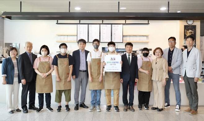 김인완 기획본부장(왼쪽에서 다섯번째), 천창수 울산광역시 교육감(오른쪽에서 다섯번째), 김인환 찬솔 사회적협동조합 대표(오른쪽 두번째)등 관계자들이 ‘발자취 프로젝트’ 1호점 현판식에서 기념사진을 촬영하는 모습 [사진 = 한국동서발전]