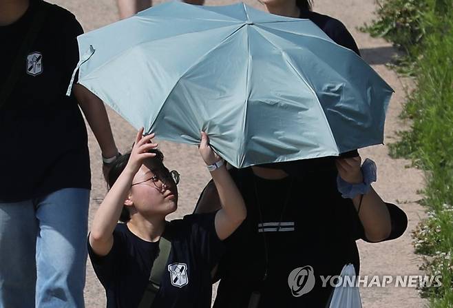 '나도 좀 쓰자' (대구=연합뉴스) 윤관식 기자 = 무더운 날씨를 보인 지난 15일 오후 대구 강창교 인근 금호강 둔치에서 열린 계명대학교 'WALK 124' 걷기 행사에 참여한 학생들이 양산을 쓰고 걷고 있다. 2023.5.15 psik@yna.co.kr