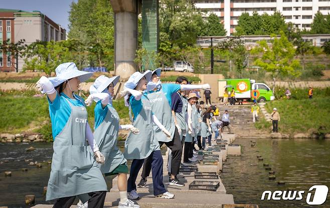 코웨이 임직원 봉사자가 안양천 다리에서 'EM흙공'을 던지는 모습(코웨이 제공)