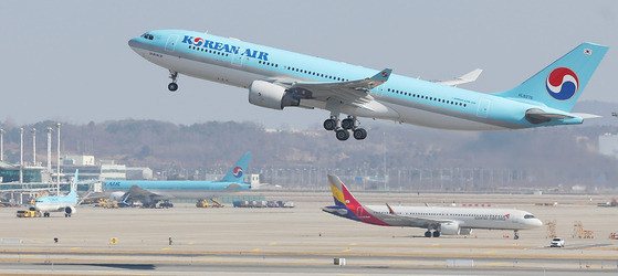 A Korean Air plane takes off at Incheon International Airport with an Asiana Airlines plane taxing behind. [YONHAP]