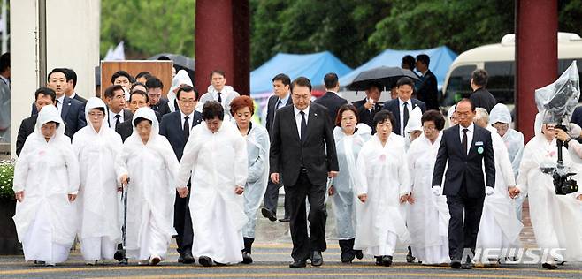 [광주=뉴시스] 홍효식 기자 = 윤석열 대통령이 18일 광주 북구 국립5·18민주묘지에서 열린 제43주년 5·18민주화운동 기념식에 오월어머니회 회원들과 함께 입장하고 있다. (대통령실통신사진기자단) 2023.05.18. yesphoto@newsis.com