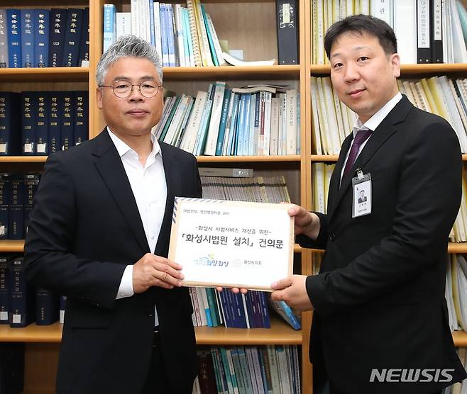 [화성=뉴시스] 화성시 박형일 자치행정국장(사진 왼쪽)이 법원행정처 고원혁 기획운영담당관에게 건의문을 전달하고 있다. (사진 = 화성시 제공)