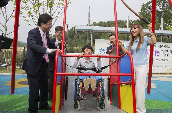 지난 2016년 9월 세종누리학교 교정에서 열린 휠체어그네 기부식에서 조수미(오른쪽)씨와 최교진 세종시교육감(왼쪽)이 휠체어 그네를 밀고 있다. 세종시교육청 제공